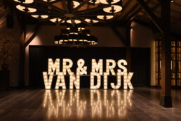 LICHTLETTERS IN EEN FEEST ZAAL MET DE ACHTERNAAM VAN HET BRUIDSPAAR