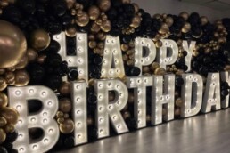 LICHTLETTERS VOOR EEN VERJAARDAG OMRINGD MET GOUD ZWARTE BALONNEN