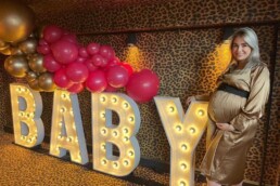 LICHTLETTERS BABY MET BALLONNNEN EN EEN ZWANGERE VROUW MET EEN GOUDEN JURK AAN